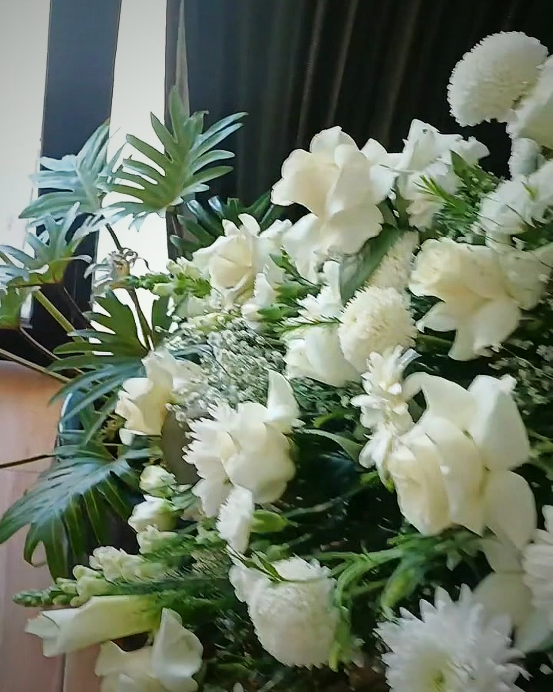 Arreglo funerario blanco con follaje